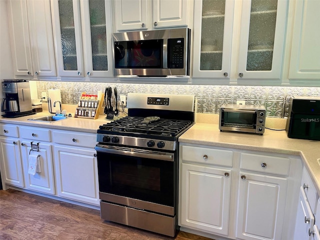 kitchen featuring sink, appliances with stainless steel finishes, white cabinets, and decorative backsplash