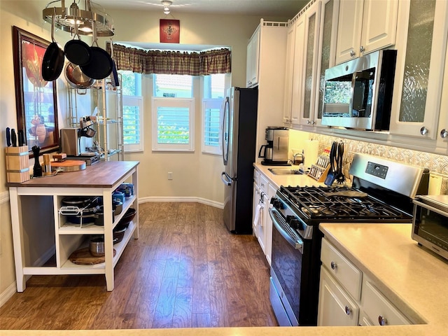 kitchen featuring white cabinetry, stainless steel appliances, sink, dark wood-type flooring, and decorative backsplash