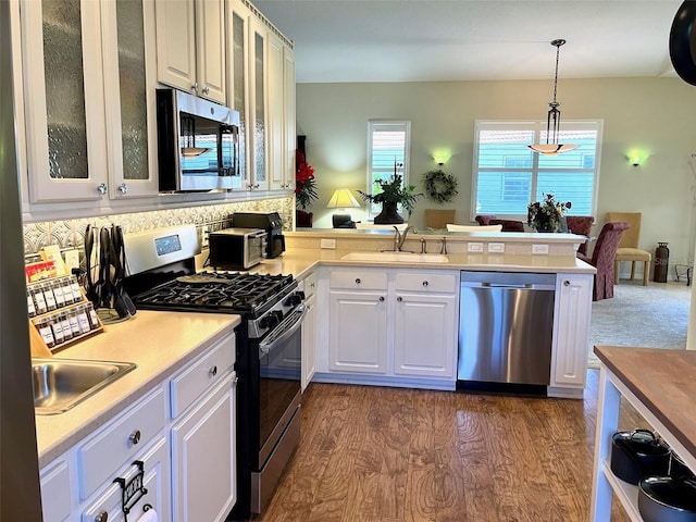 kitchen with sink, white cabinets, stainless steel appliances, and pendant lighting