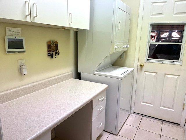 washroom featuring light tile patterned flooring, cabinets, and stacked washer / drying machine