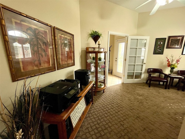 living area featuring carpet, a healthy amount of sunlight, a towering ceiling, and ceiling fan