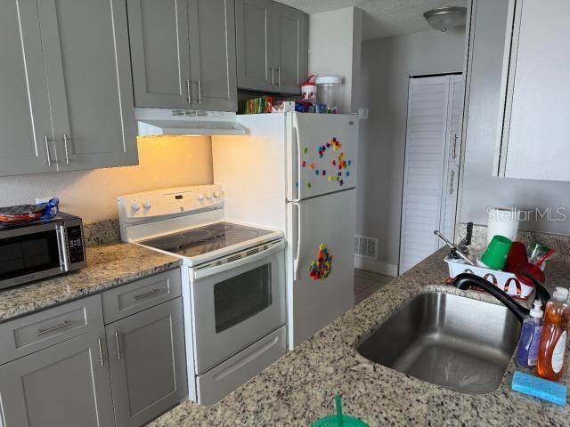 kitchen with white appliances, gray cabinets, and sink