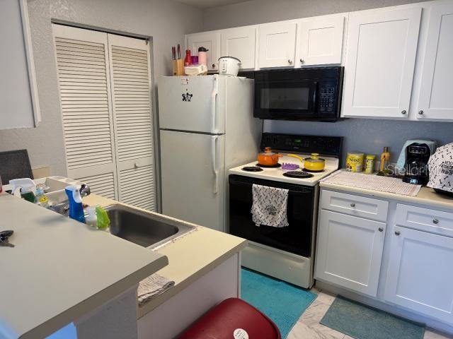 kitchen featuring white cabinetry, sink, and white appliances