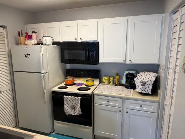 kitchen with white refrigerator, white cabinets, and electric stove