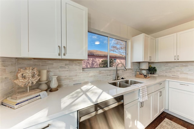 kitchen featuring tasteful backsplash, white cabinets, dishwasher, light countertops, and a sink