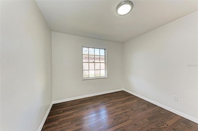 empty room with dark wood finished floors and baseboards