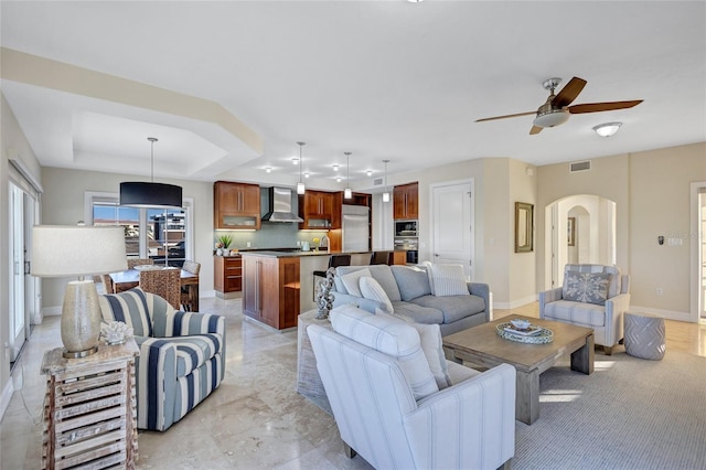 living room featuring ceiling fan and a raised ceiling