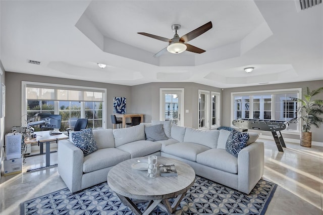 living room with ceiling fan and a raised ceiling