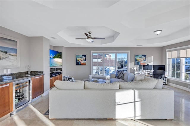 living room featuring a wealth of natural light, wet bar, beverage cooler, and ceiling fan