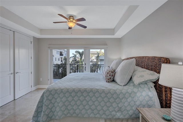 bedroom with a raised ceiling, light tile patterned flooring, access to exterior, and ceiling fan