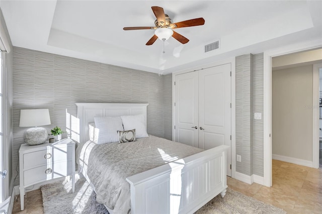 bedroom with ceiling fan, a raised ceiling, and a closet