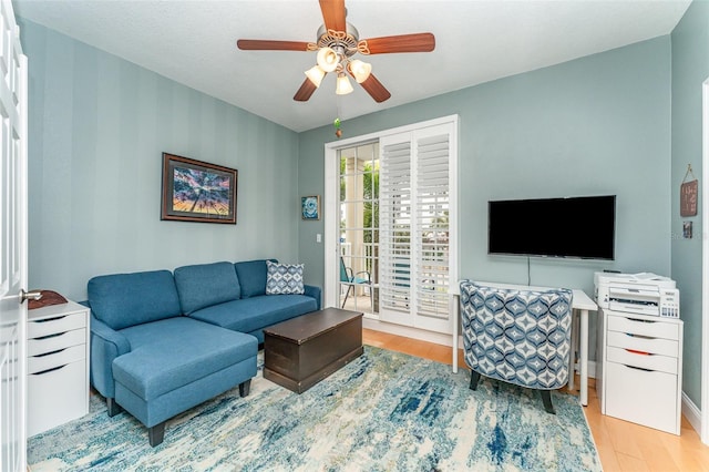 living room featuring ceiling fan, wood finished floors, and baseboards