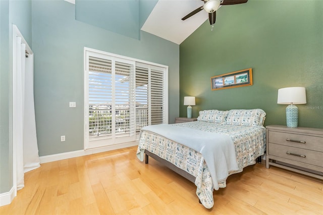 bedroom with baseboards, light wood-style flooring, a high ceiling, a ceiling fan, and access to exterior