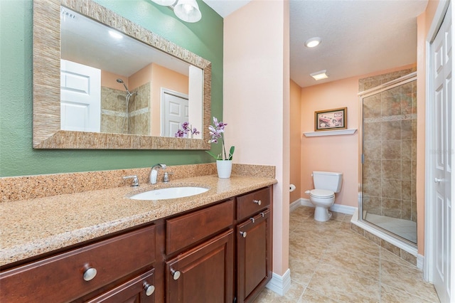 bathroom featuring baseboards, toilet, vanity, tile patterned floors, and a stall shower