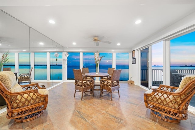 sunroom / solarium featuring a water view and ceiling fan