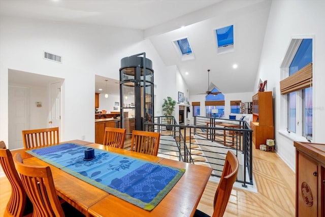 dining room featuring a skylight, high vaulted ceiling, and ceiling fan