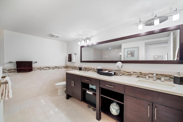 bathroom featuring walk in shower, toilet, tile walls, vanity, and tile patterned flooring