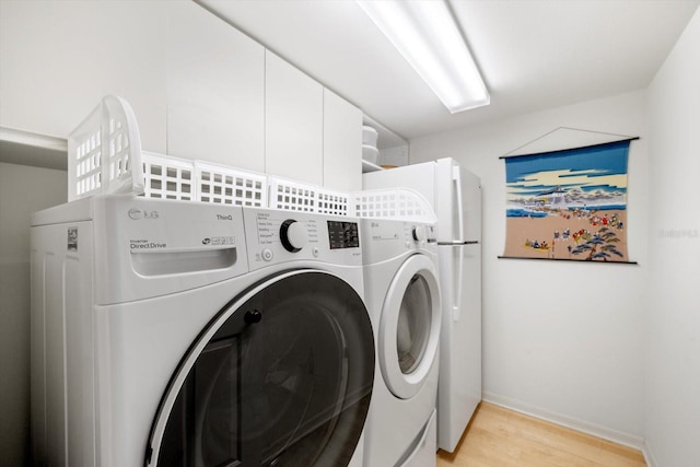 laundry area with light hardwood / wood-style floors and washer and dryer