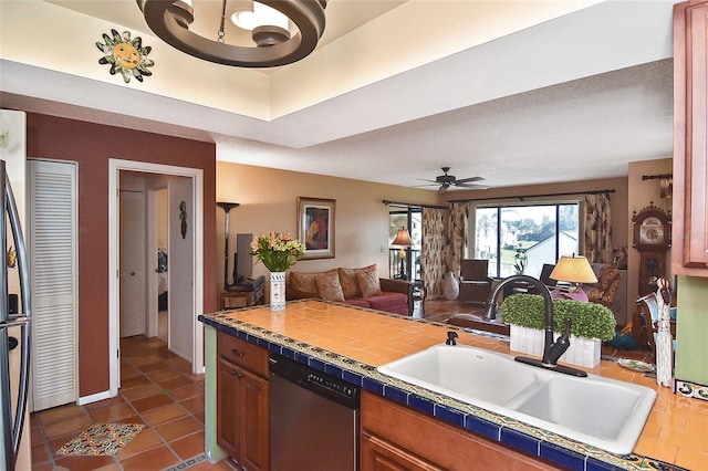 kitchen featuring sink, dishwasher, ceiling fan, tile counters, and dark tile patterned flooring