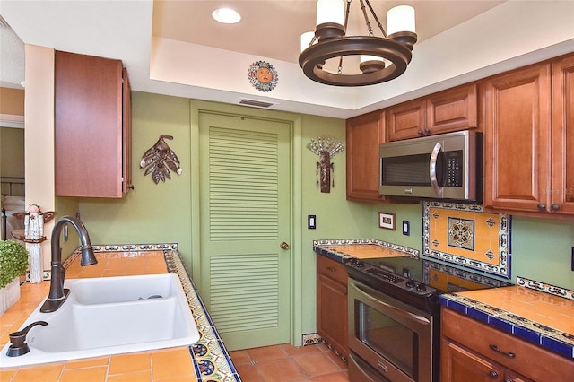 kitchen with appliances with stainless steel finishes, sink, tile countertops, and decorative backsplash