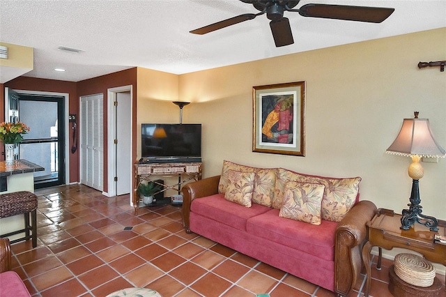 tiled living room with ceiling fan and a textured ceiling