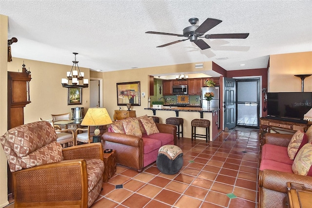 living room featuring dark tile patterned flooring, ceiling fan with notable chandelier, and a textured ceiling