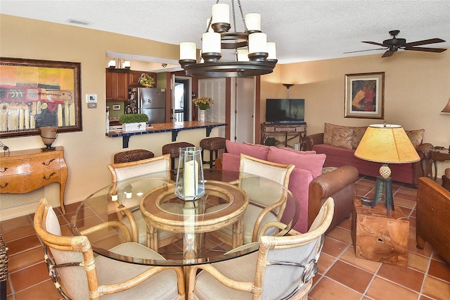 dining space featuring ceiling fan with notable chandelier, light tile patterned floors, and a textured ceiling