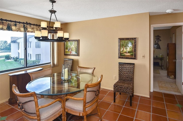 dining space with a notable chandelier, dark tile patterned flooring, and a textured ceiling