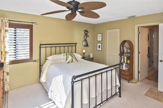 bedroom with light colored carpet, ceiling fan, and a closet