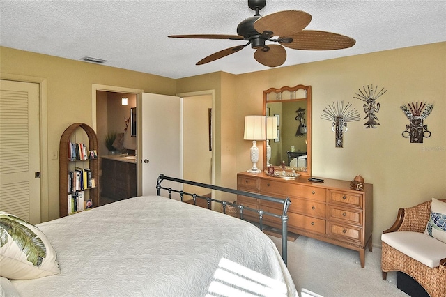 carpeted bedroom featuring ceiling fan, a textured ceiling, and ensuite bath