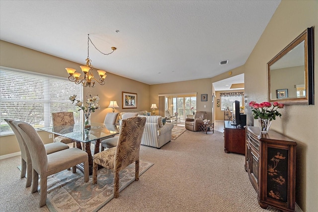 dining space with light carpet, a notable chandelier, and a textured ceiling