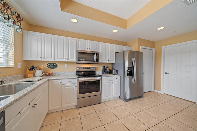 kitchen featuring white cabinetry, sink, light tile patterned floors, and stainless steel appliances