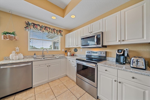 kitchen featuring sink, light tile patterned floors, stainless steel appliances, and white cabinets