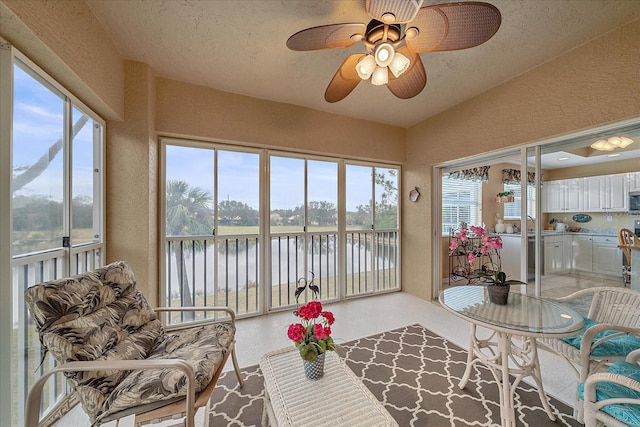 sunroom / solarium with ceiling fan, vaulted ceiling, a healthy amount of sunlight, and a water view