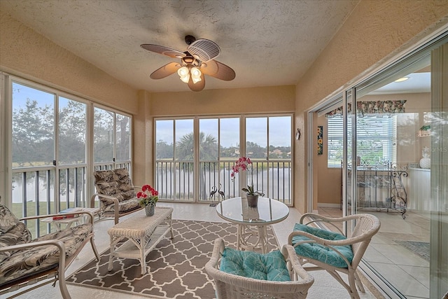 sunroom / solarium featuring a water view and ceiling fan