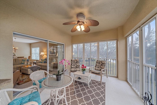 sunroom featuring ceiling fan with notable chandelier