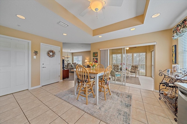 dining room with a raised ceiling, light tile patterned floors, and ceiling fan