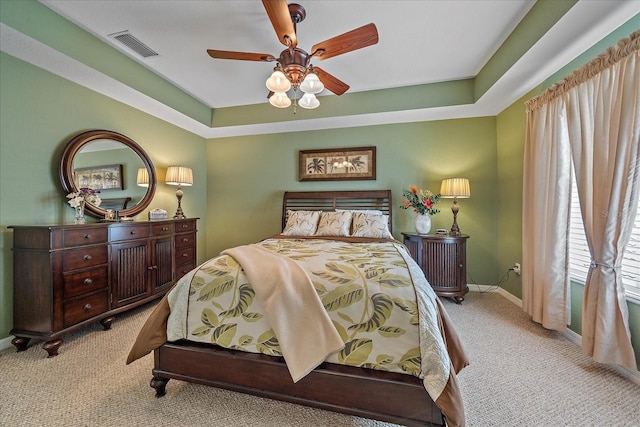 bedroom with a tray ceiling, light colored carpet, and ceiling fan