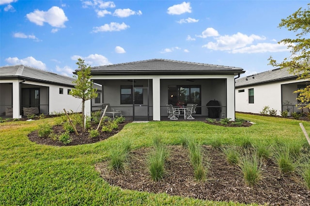 rear view of property featuring ceiling fan, a sunroom, a patio area, and a lawn