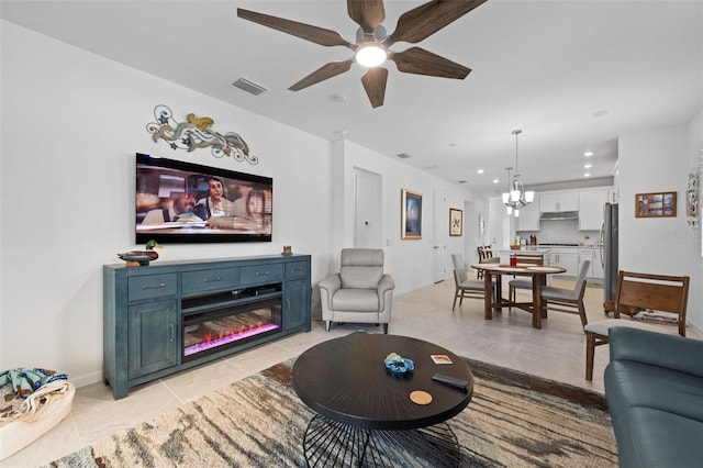 tiled living room with ceiling fan with notable chandelier