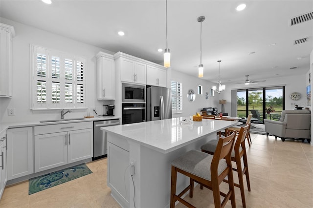 kitchen featuring white cabinetry, sink, stainless steel appliances, and a kitchen island