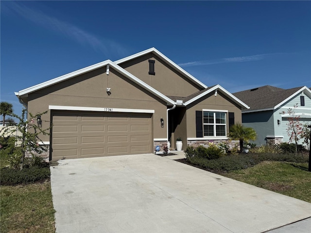 single story home featuring an attached garage, stone siding, driveway, and stucco siding