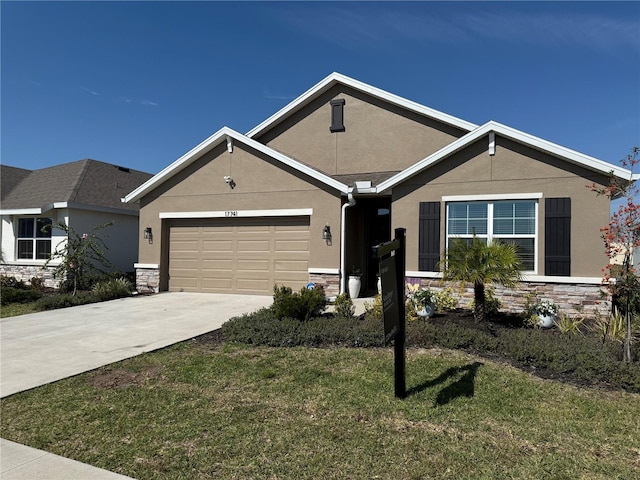 ranch-style house with stucco siding, a front yard, a garage, stone siding, and driveway