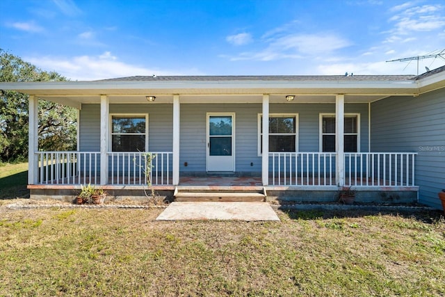 entrance to property with a porch and a yard