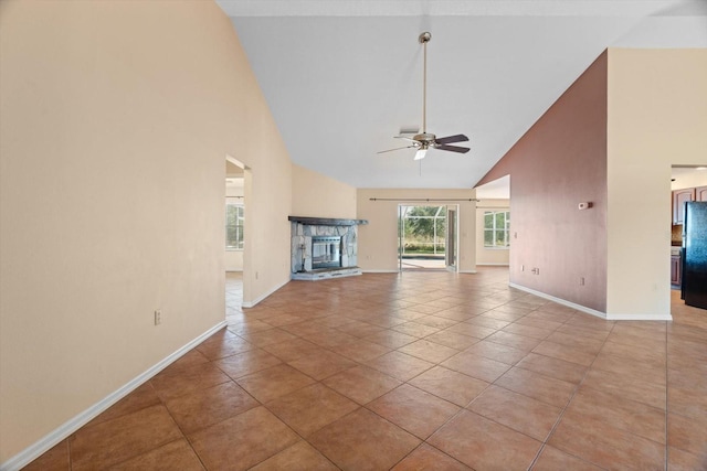 unfurnished living room featuring ceiling fan, a stone fireplace, light tile patterned floors, and high vaulted ceiling