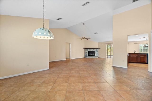 unfurnished living room with lofted ceiling, light tile patterned floors, sink, ceiling fan, and a fireplace