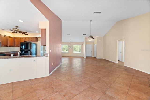 kitchen with black refrigerator, ceiling fan, vaulted ceiling, and light tile patterned floors