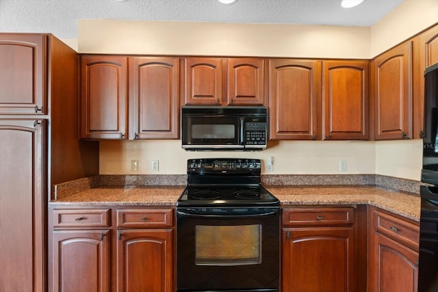 kitchen with a textured ceiling, dark stone counters, and black appliances