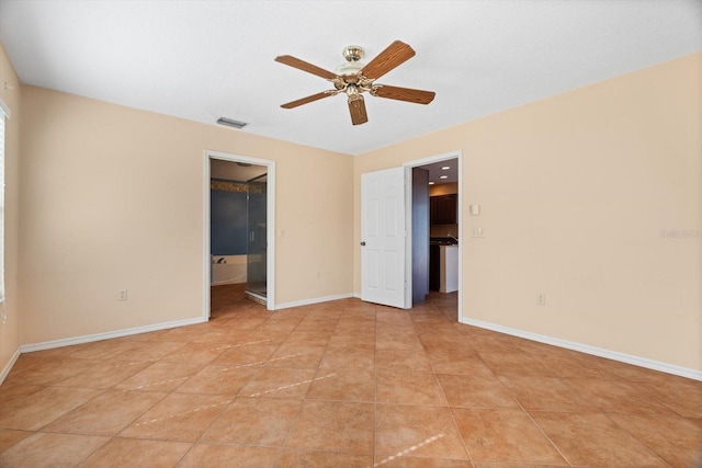 unfurnished bedroom with light tile patterned floors, a walk in closet, ceiling fan, and ensuite bathroom