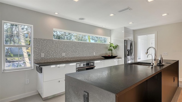 kitchen with tasteful backsplash, white cabinetry, sink, stainless steel fridge, and wall oven